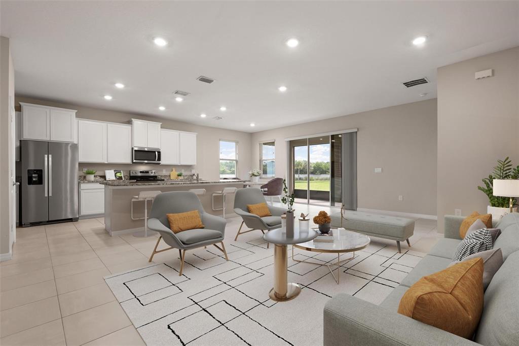 An open-concept living and kitchen area features light tile flooring and recessed ceiling lighting — 431 158TH STREET E, BRADENTON, FL