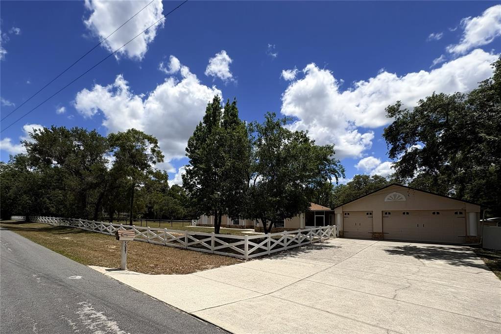 A single-story house with a two-car garage and a white fence along the front yard — 5085 BONE LANE, BROOKSVILLE, FL