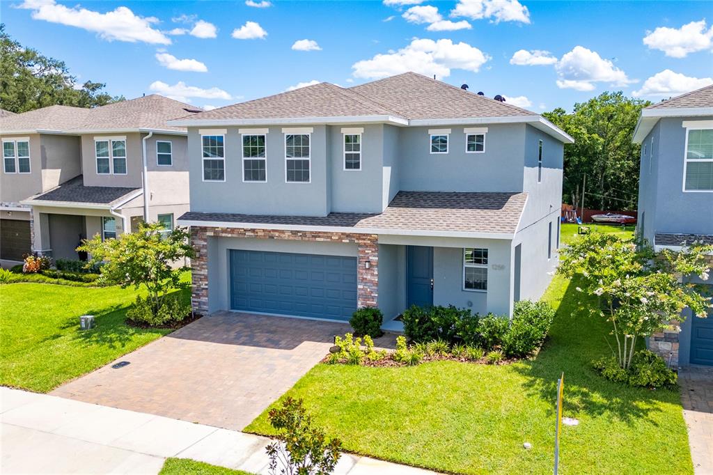 A two-story suburban house with a gray stucco exterior, stone accents, and a paved driveway — 1259 ASH TREE COVE, CASSELBERRY, FL