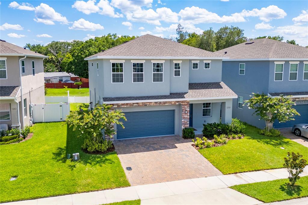 A two-story suburban house with a gray stucco exterior, stone accents, and a paved driveway — 1259 ASH TREE COVE, CASSELBERRY, FL