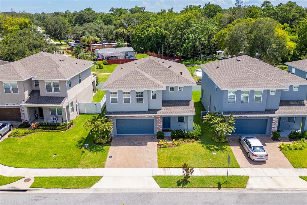 An aerial view shows three two-story suburban houses with paved driveways and green lawns — 1259 ASH TREE COVE, CASSELBERRY, FL