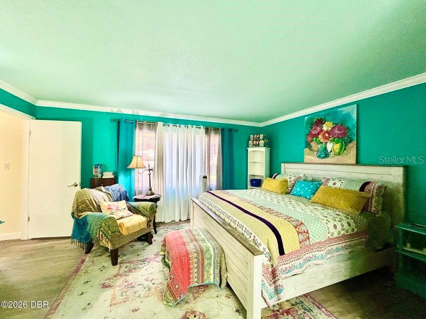 A bedroom features teal walls, a large bed with a patterned quilt, and a patterned rug — 1 TOMOKA OAKS BOULEVARD UNIT 119, ORMOND BEACH, FL