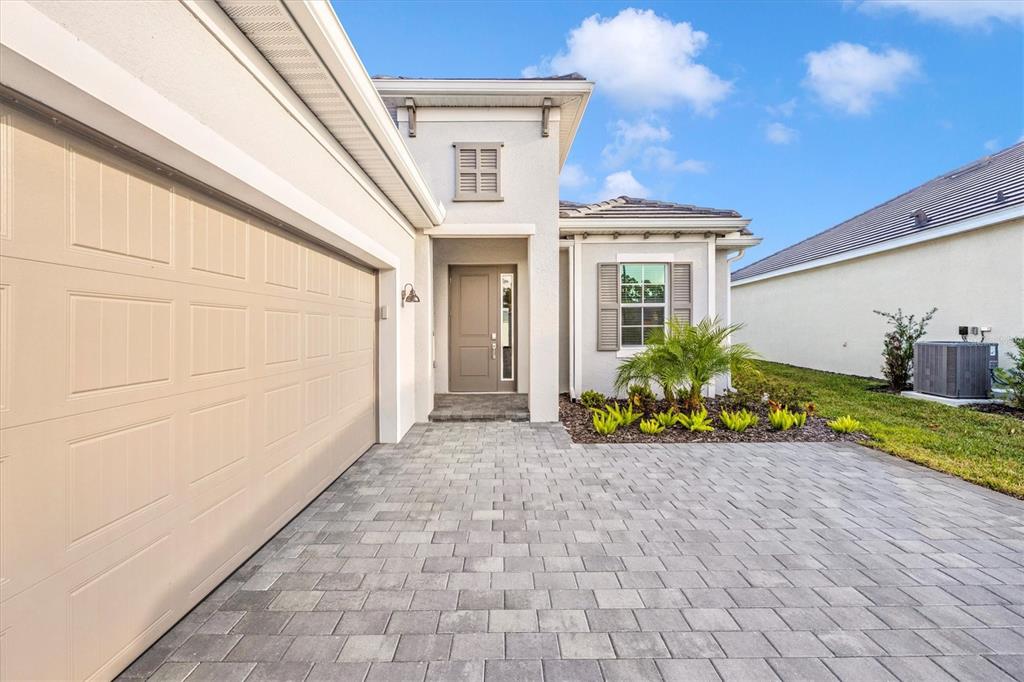 A paved driveway leads to the front entrance and garage of a single-story suburban home — 12950 TULUM LOOP, VENICE, FL