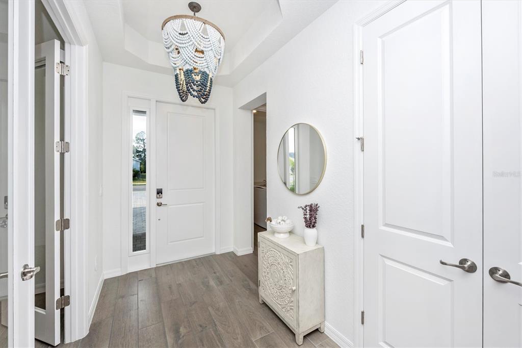 An entryway with wood-look tile flooring, a beaded chandelier, and a white console table — 12950 TULUM LOOP, VENICE, FL