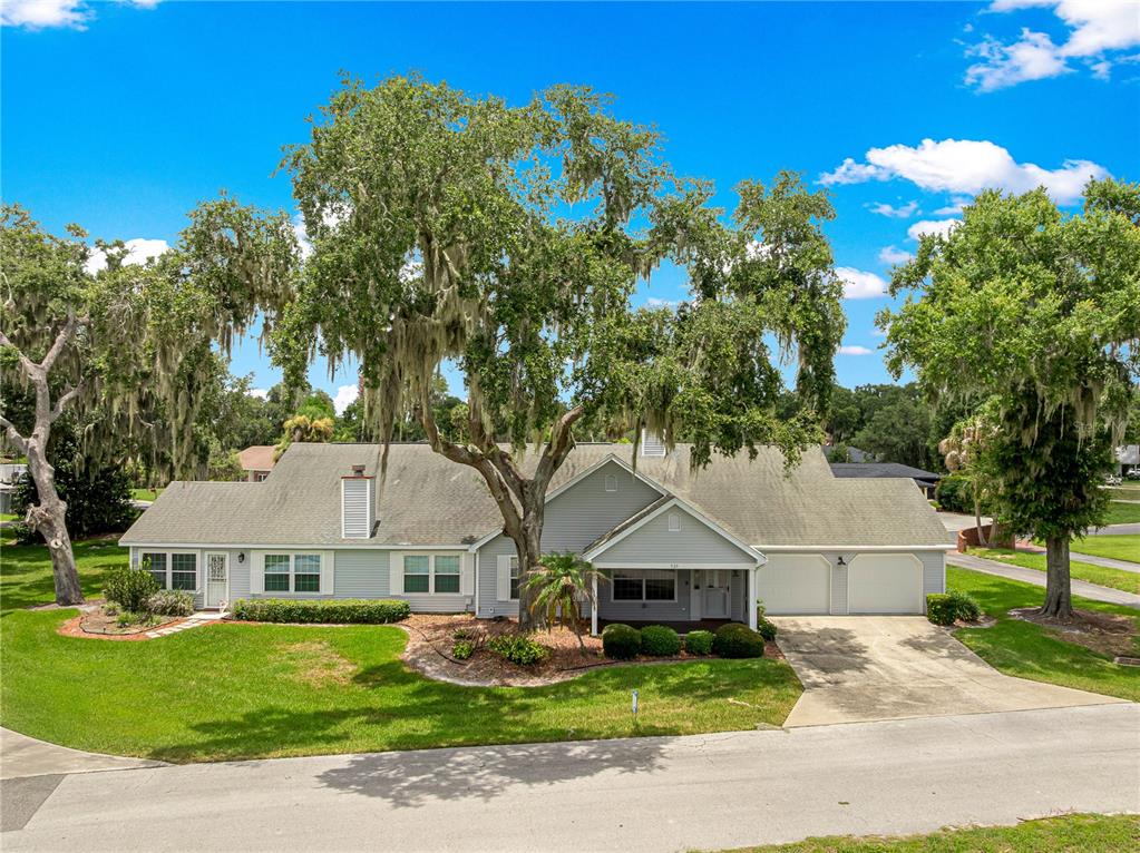 A single-story house with gray siding, a two-car garage, and large trees in the yard — 925 BEVERLY HARBORS DRIVE, LEESBURG, FL