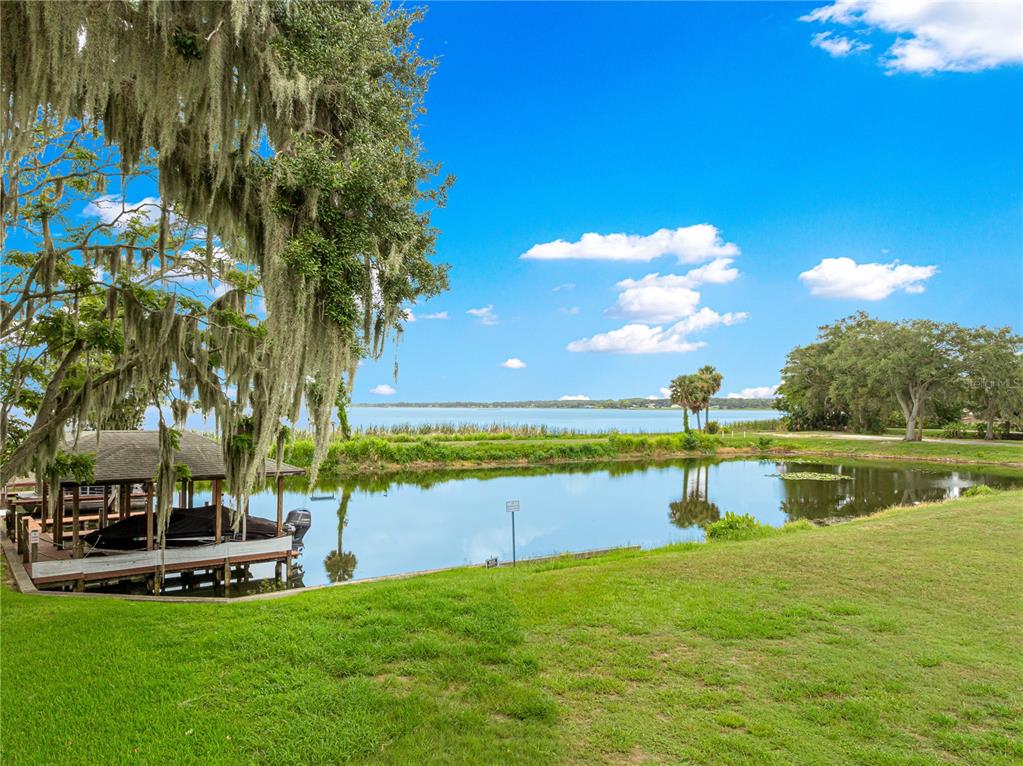 A boat dock sits on a small pond with a large lake in the background — 925 BEVERLY HARBORS DRIVE, LEESBURG, FL