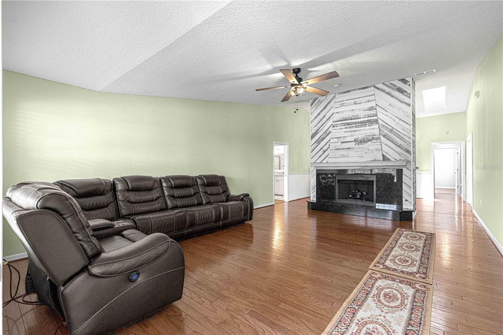 A living room features a large sectional sofa, hardwood floors, and a wood-paneled fireplace — 925 BEVERLY HARBORS DRIVE, LEESBURG, FL