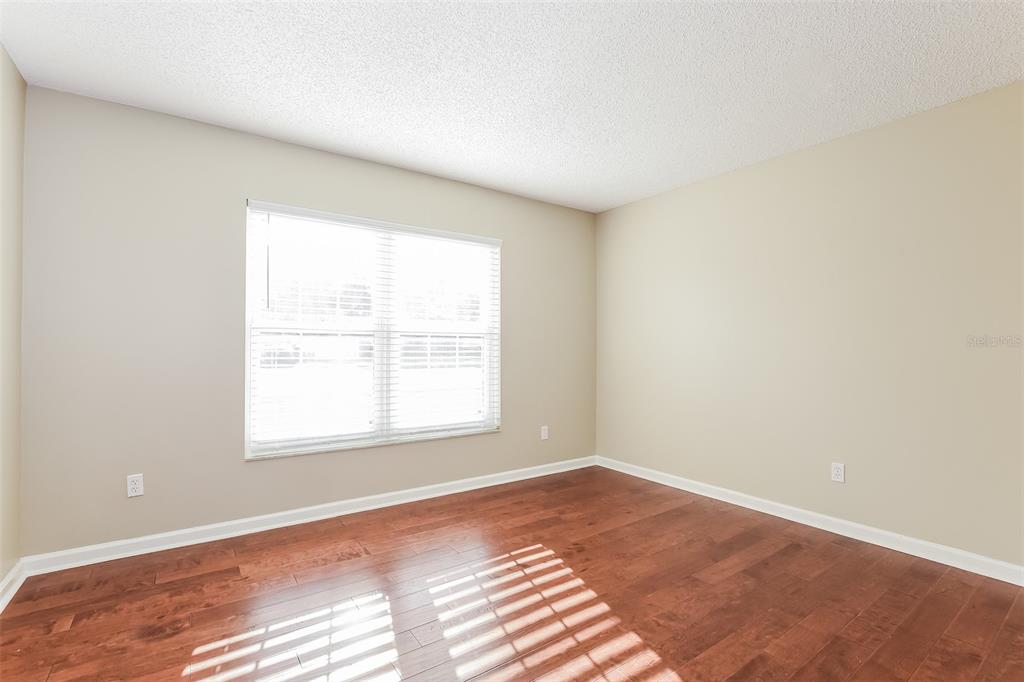 An empty bedroom features light beige walls, dark hardwood flooring, and a large window — 5409 ALBERT DRIVE, WINTER PARK, FL