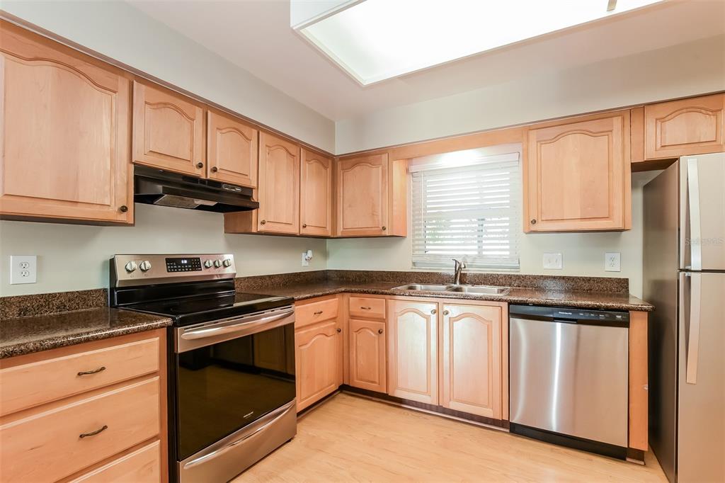 A kitchen features light wood cabinets, granite countertops, and stainless steel appliances — 5409 ALBERT DRIVE, WINTER PARK, FL