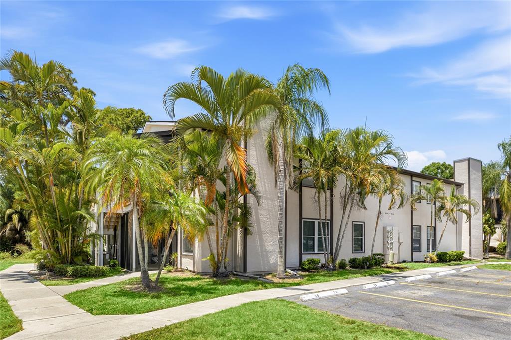 A covered patio features a white front door, two folding chairs, and a small grill — 3634 59TH AVENUE W, BRADENTON, FL