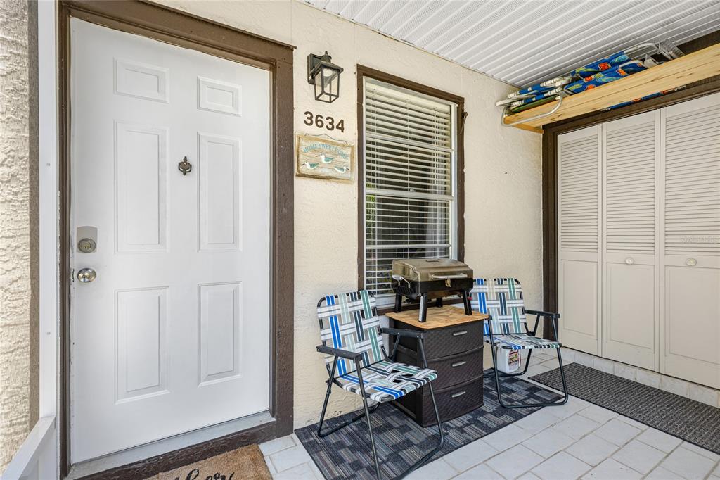 A living room with tile floors, a gray sofa, a rattan coffee table, and dining area — 3634 59TH AVENUE W, BRADENTON, FL