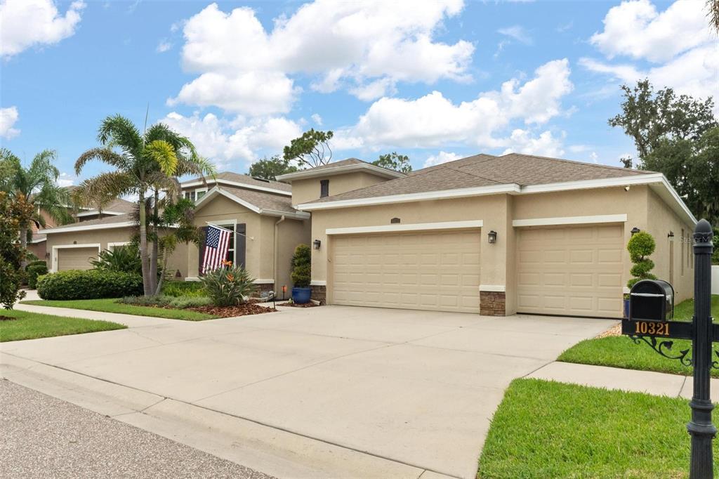 A tan, single-story house with a three-car garage and a paved driveway — 10321 RIVERDALE RISE DRIVE, RIVERVIEW, FL