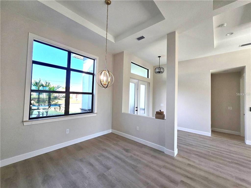 An interior view of a dining area with wood-look flooring, a tray ceiling, and windows — 703 BOUNDARY BOULEVARD, ROTONDA WEST, FL