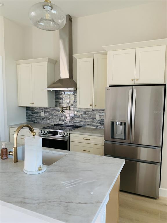 A kitchen features white cabinets, stainless steel appliances, a marble-look island, and a tile backsplash — 703 BOUNDARY BOULEVARD, ROTONDA WEST, FL