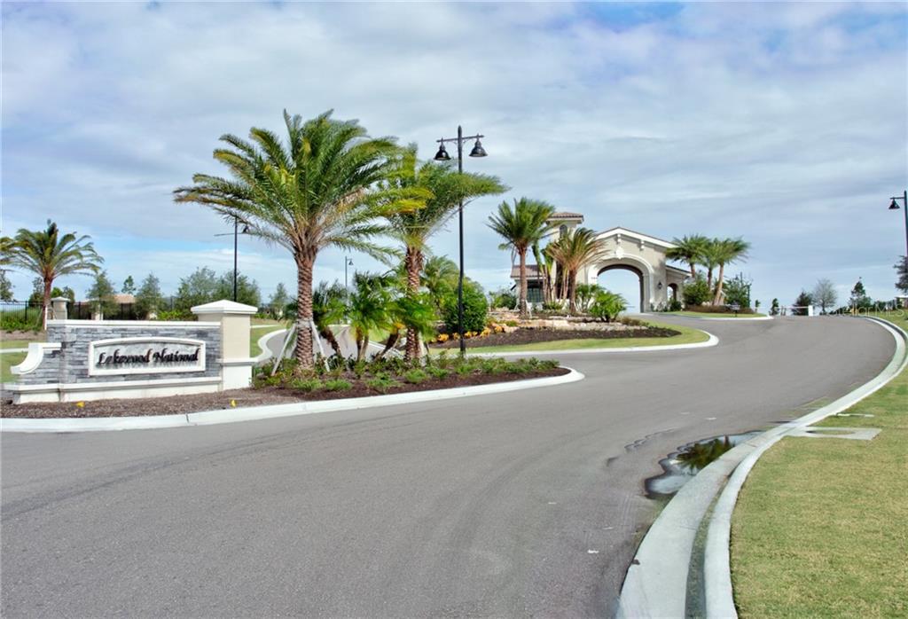 The entrance to a gated community features a stone sign, palm trees, and a gatehouse — 5558 PALMER CIRCLE UNIT 106, BRADENTON, FL