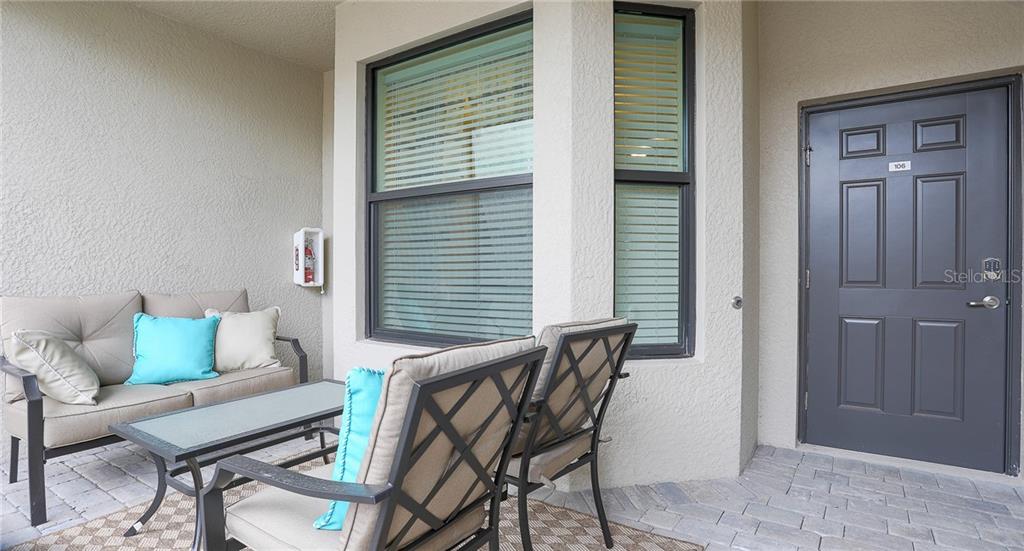 A patio features a sofa, two chairs, a coffee table, and a dark gray entry door — 5558 PALMER CIRCLE UNIT 106, BRADENTON, FL