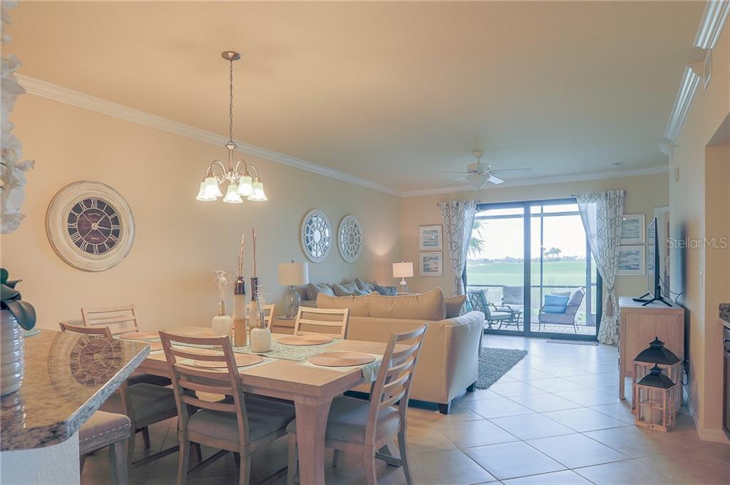 A dining area with a wooden table opens into a living room with sliding glass doors — 5558 PALMER CIRCLE UNIT 106, BRADENTON, FL