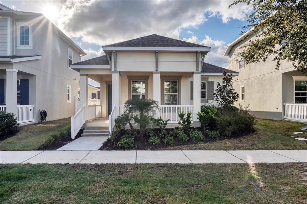 A single-story house with a white porch and landscaping sits behind a concrete sidewalk — 724 WINTERSIDE DRIVE, APOLLO BEACH, FL