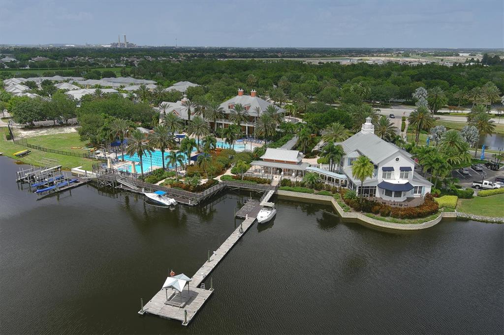 An aerial view shows a waterfront clubhouse with a pool, boat docks, and surrounding landscaping — 724 WINTERSIDE DRIVE, APOLLO BEACH, FL