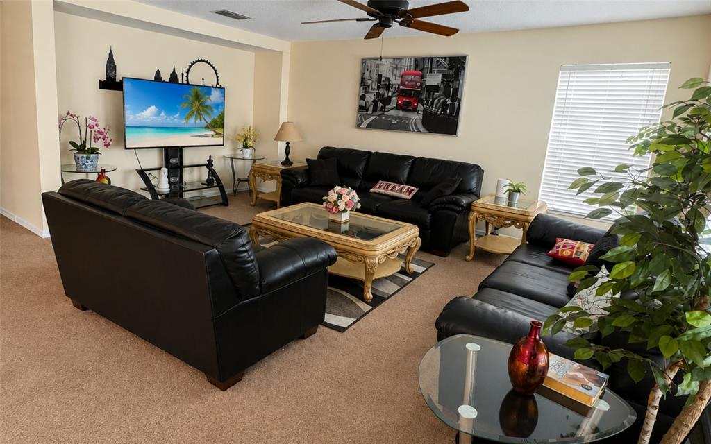 A living room features three black leather sofas, a glass-topped coffee table, and a television — 133 RONA LANE, DAVENPORT, FL