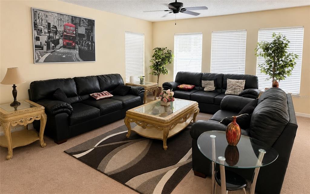 A living room features three black leather sofas, a glass-topped coffee table, and area rug — 133 RONA LANE, DAVENPORT, FL
