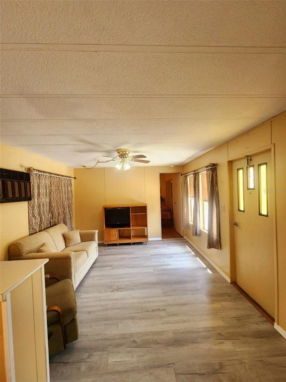A living room features light wood-look flooring, a beige sofa, and a wooden media console — 35015 MAJOR DADE, DADE CITY, FL