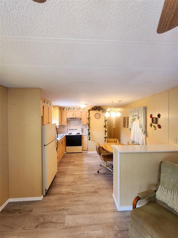 A kitchen with light wood cabinets, white appliances, and a dining area with a round table — 35015 MAJOR DADE, DADE CITY, FL
