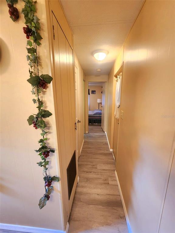 A narrow hallway with light wood-look flooring leads to a bedroom at the end — 35015 MAJOR DADE, DADE CITY, FL