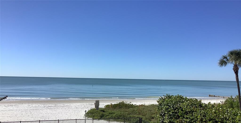 An elevated view of a swimming pool, lounge chairs, and a sandy beach with dunes — 14900 GULF BOULEVARD UNIT 113, MADEIRA BEACH, FL