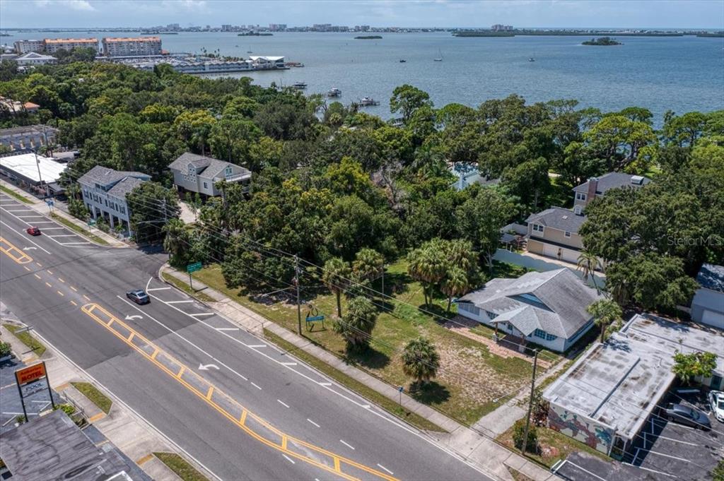 An aerial view shows a coastal property with a house, trees, and a nearby bay — 1040 BROADWAY, DUNEDIN, FL
