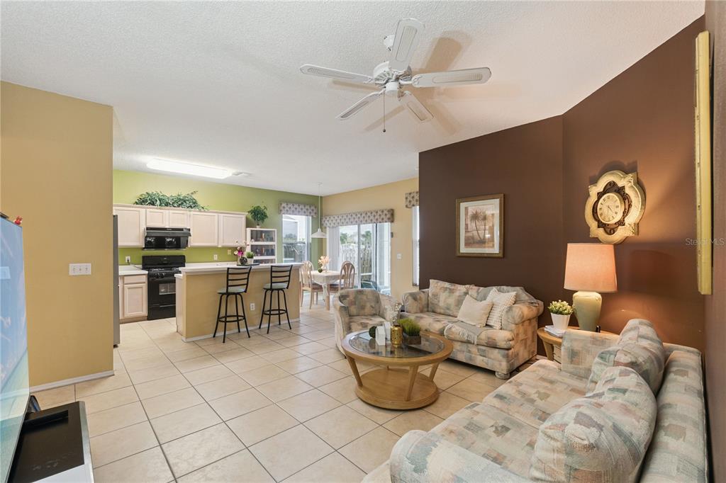 An open-concept living room and kitchen area features tile flooring, a ceiling fan, and furniture — 765 JAYBEE AVENUE, DAVENPORT, FL