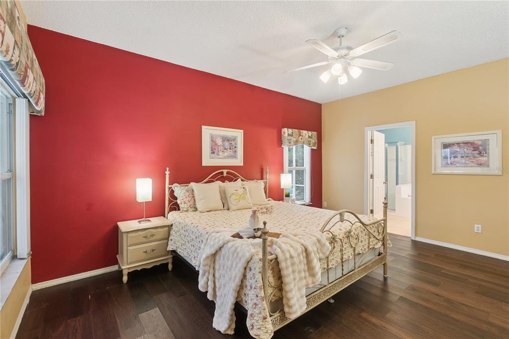 A bedroom features a metal bed frame, dark wood floors, and a red accent wall — 765 JAYBEE AVENUE, DAVENPORT, FL