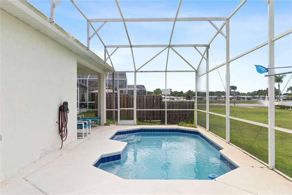 A screened-in patio features a small swimming pool and a view of a grassy field — 765 JAYBEE AVENUE, DAVENPORT, FL