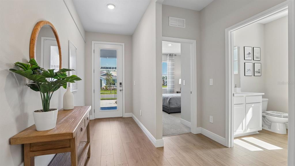 A bright entryway features light wood flooring, a console table, and a view into a bathroom — 35596 BRICK CHURCH LOOP, DADE CITY, FL