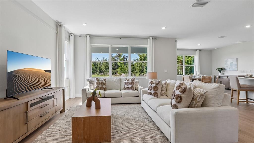 A bright living room features a white sofa, a wooden coffee table, and a television — 35596 BRICK CHURCH LOOP, DADE CITY, FL
