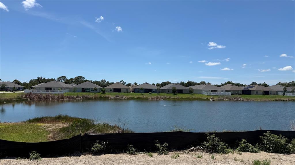 A pond sits in front of a row of suburban houses under a blue sky — 2663 AVERLAND LOOP, NORTH PORT, FL