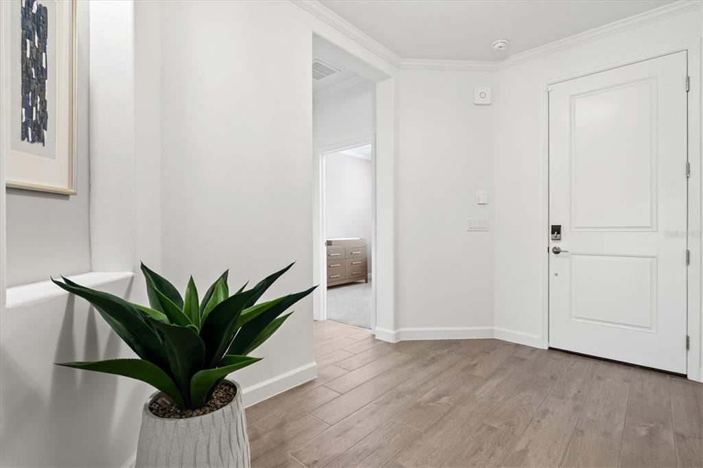 An entryway features white walls, wood-look tile flooring, a potted plant, and a front door — 5144 SPOTTED SEAL LANE, BRADENTON, FL