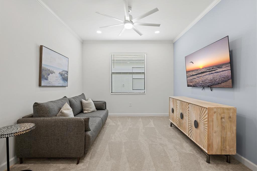 A living room features a gray sofa, a wooden media console, and a wall-mounted television — 5144 SPOTTED SEAL LANE, BRADENTON, FL