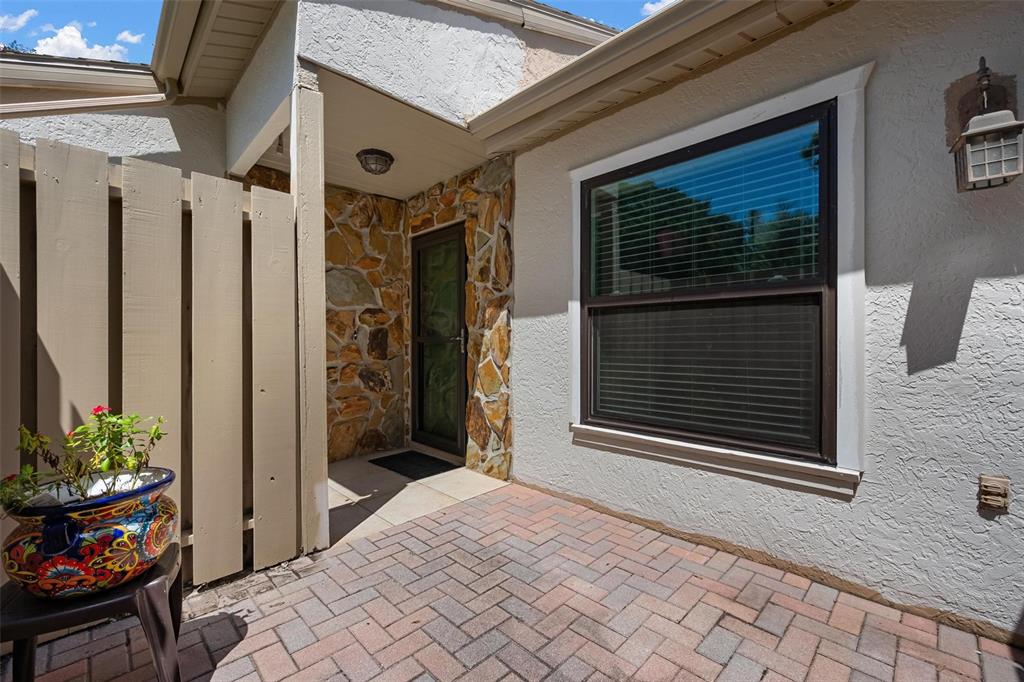 A brick patio leads to a stone-accented entryway with a glass door and a window — 1554 TALLYWOOD DRIVE UNIT 7127, SARASOTA, FL