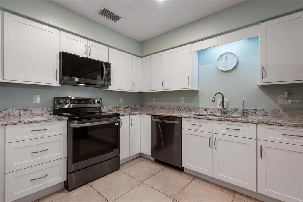 A kitchen with white cabinets, stainless steel appliances, and granite countertops — 1554 TALLYWOOD DRIVE UNIT 7127, SARASOTA, FL