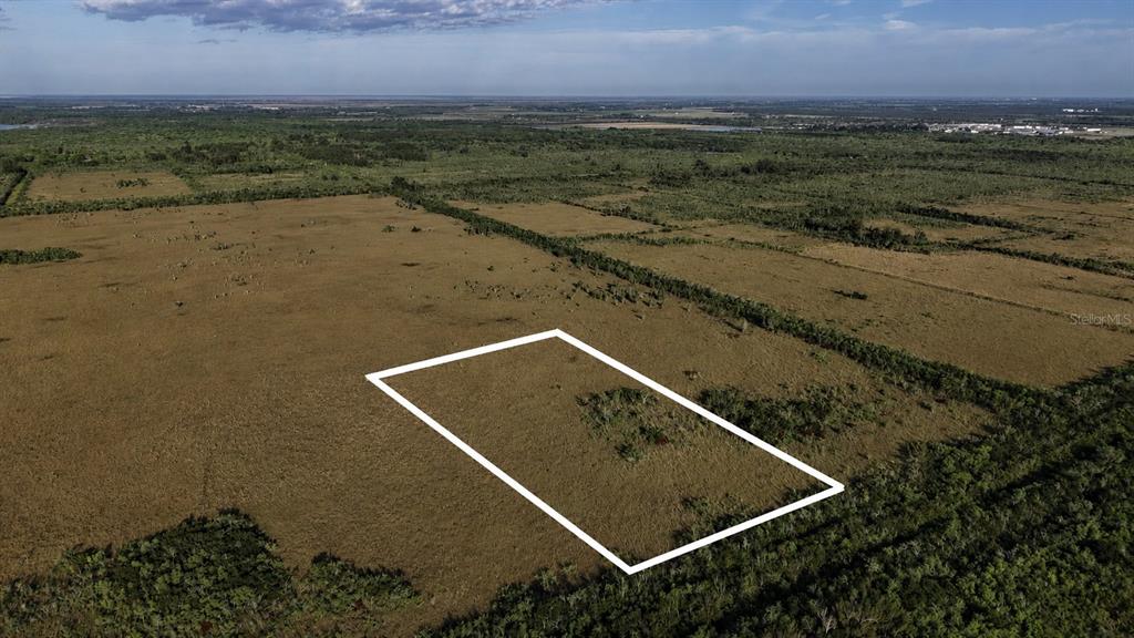 An aerial view shows a rectangular plot of land outlined in white amidst open fields — 0 UNKNOWN ROAD, HOMESTEAD, FL