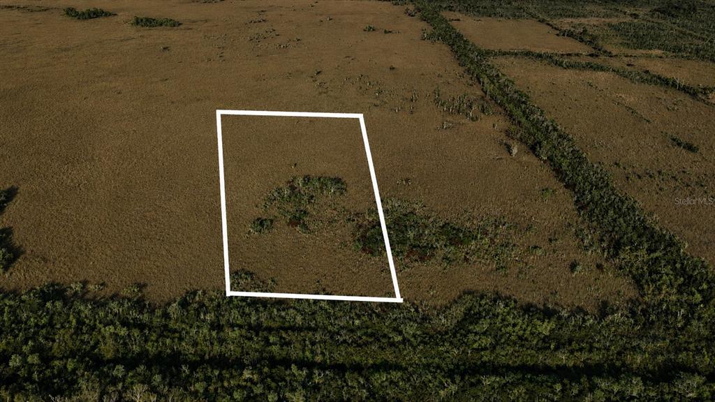 An aerial view shows a vacant, grassy lot outlined in white amidst a rural landscape — 0 UNKNOWN ROAD, HOMESTEAD, FL