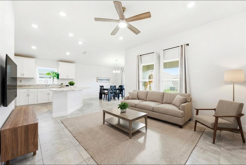 A kitchen features white cabinets, stainless steel appliances, and a large granite-topped island — 111 KRENSON BAY LOOP, WINTER HAVEN, FL