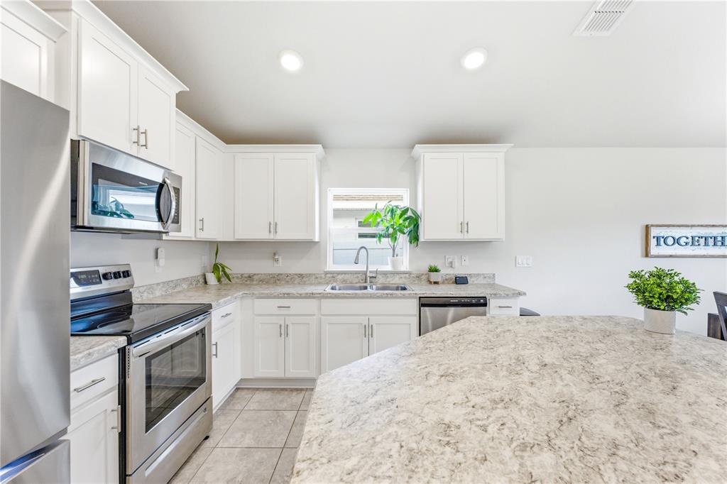 A kitchen features white cabinets, stainless steel appliances, and light-colored stone countertops — 111 KRENSON BAY LOOP, WINTER HAVEN, FL