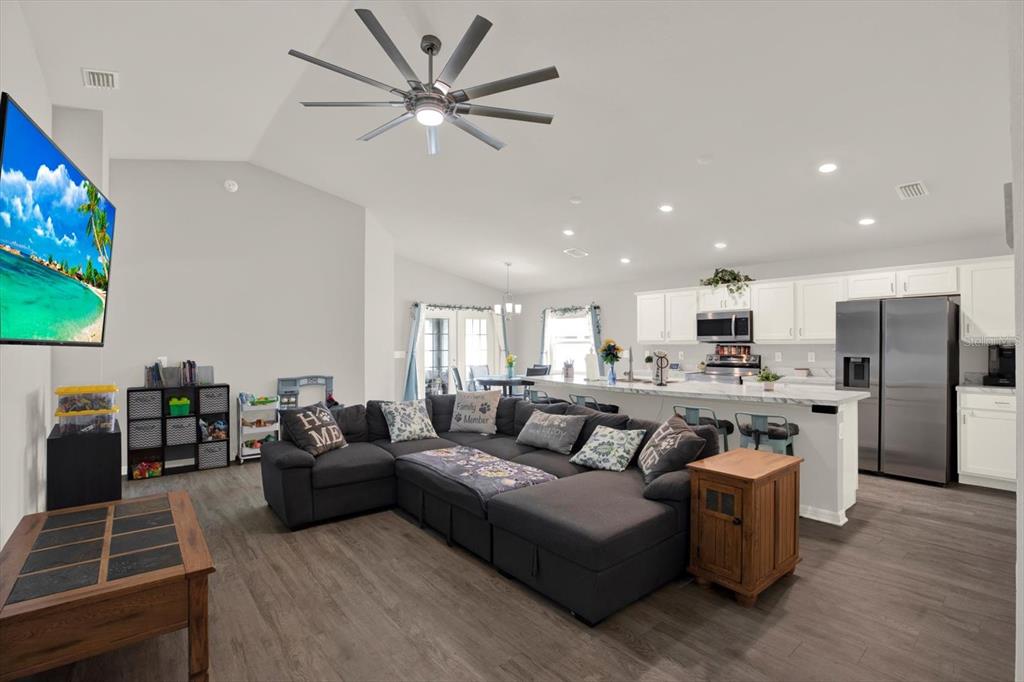 A living room with a sectional sofa opens into a kitchen with white cabinetry — 117 EAGLE SUMMIT DRIVE, RUSKIN, FL