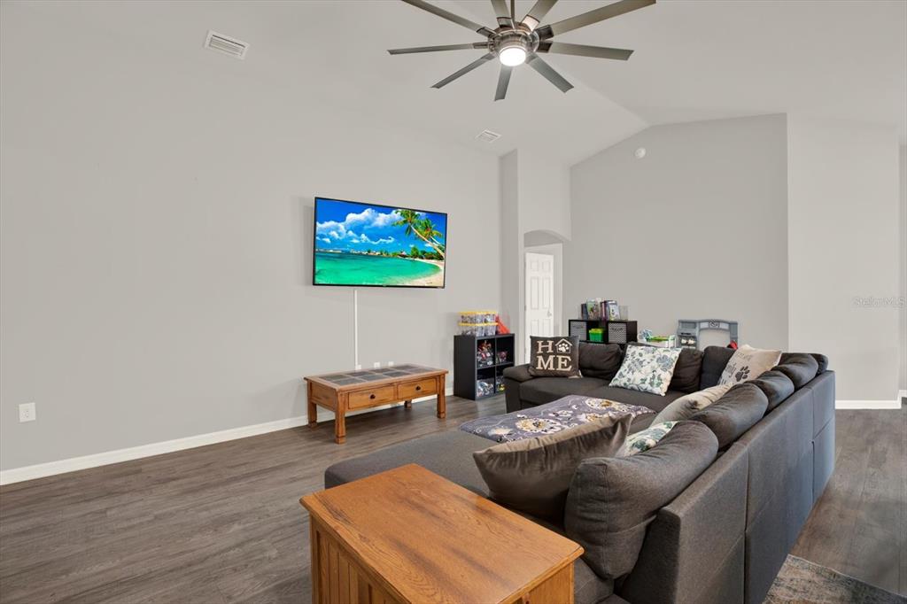 A living room features a mounted television, a sectional sofa, and a ceiling fan — 117 EAGLE SUMMIT DRIVE, RUSKIN, FL