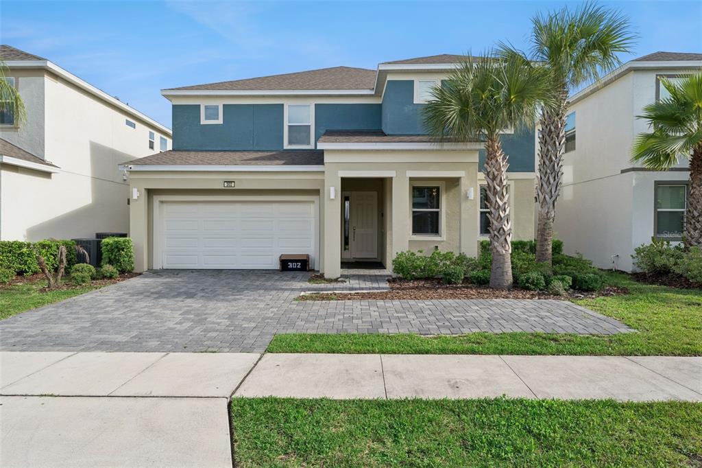 A two-story house with a blue upper facade, beige lower level, and a paved driveway — 302 MARCELLO BOULEVARD, KISSIMMEE, FL