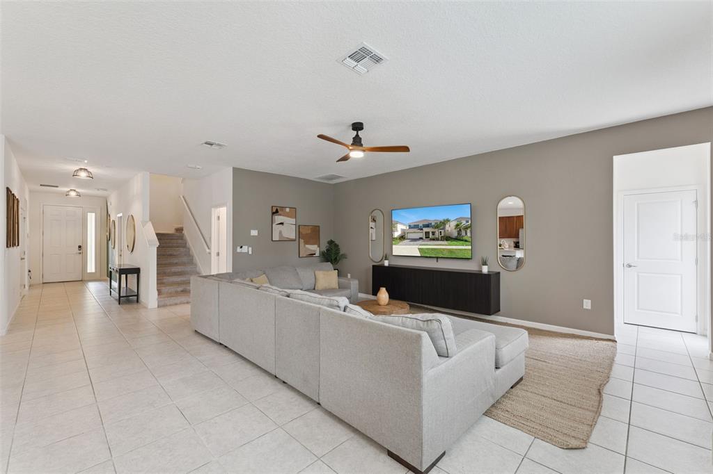 A living room features a gray sectional sofa, a wall-mounted television, and tile flooring — 302 MARCELLO BOULEVARD, KISSIMMEE, FL