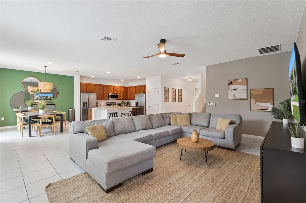 A living room with a gray sectional sofa, a round coffee table, and an open kitchen — 302 MARCELLO BOULEVARD, KISSIMMEE, FL