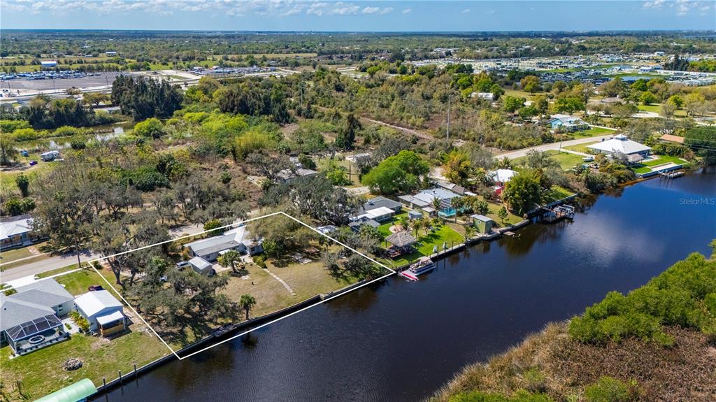 An aerial view shows a waterfront house with a large yard and a boat dock — 7754 RIVERSIDE DRIVE, PUNTA GORDA, FL